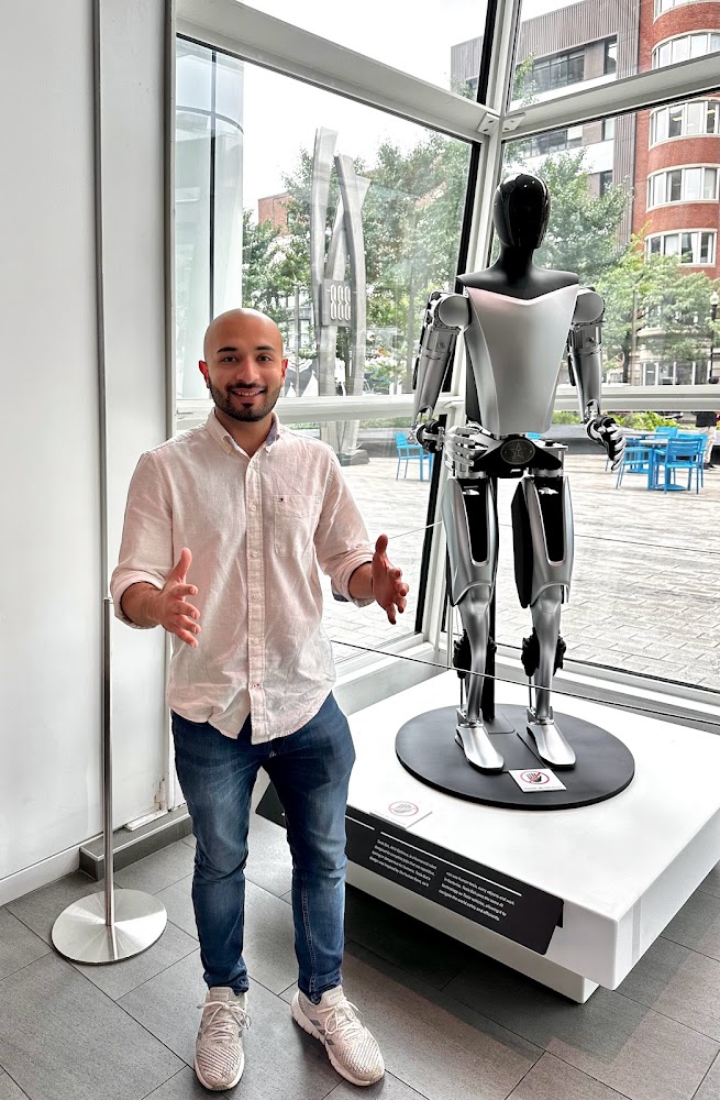 Jerrar Bukhari standing beside a Tesla Optimus humanoid robot